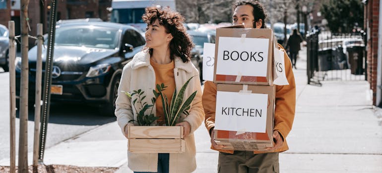 A couple carrying moving boxes