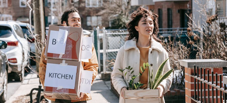 A couple carrying moving boxes