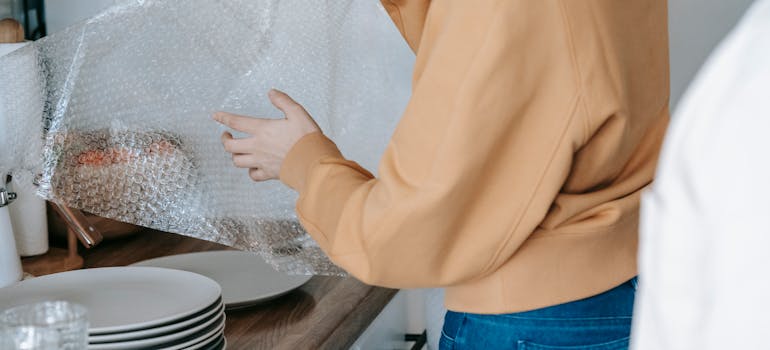 A woman wrapping a plate with a bubble wrap