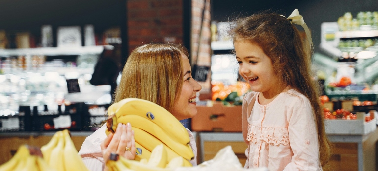 mother and daughter in a grocery store buying bananas