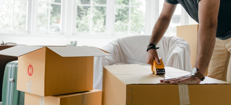 A man sealing a moving box