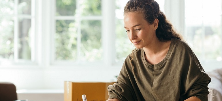 a girl writing down essential tips for moving to another state in your 20s