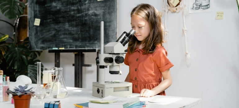 a little girl looking through a microscope