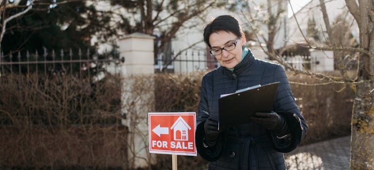 A person standing next to the sign for sale