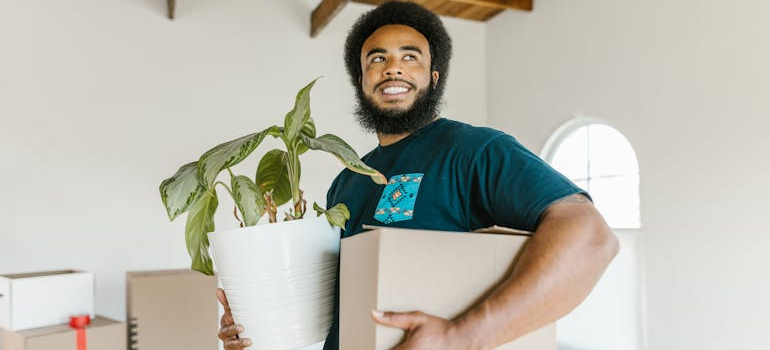 A mover holding a box and a vase, small towns in Ontario for a peaceful move