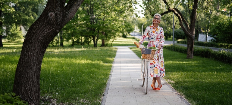 an elderly woman with a bicycle on a bike path