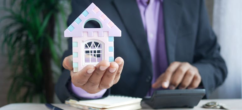 A person holding a model house